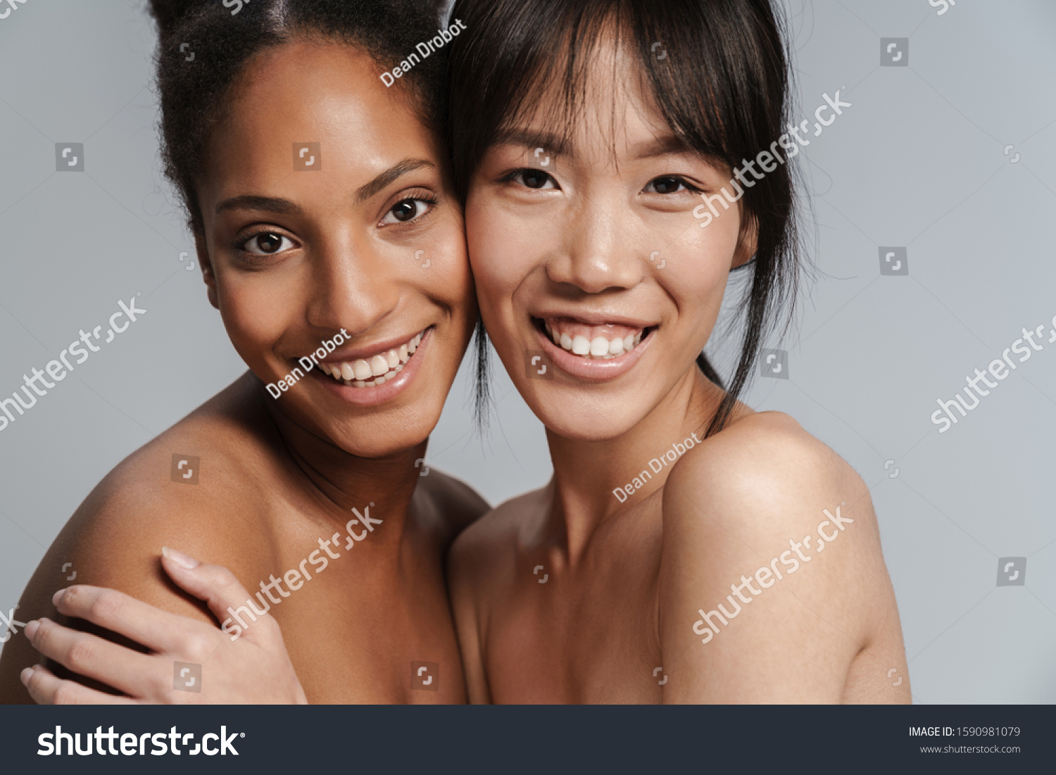 Portrait closeup of two multinational half-naked women hugging and laughing isolated over grey background #1590981079
