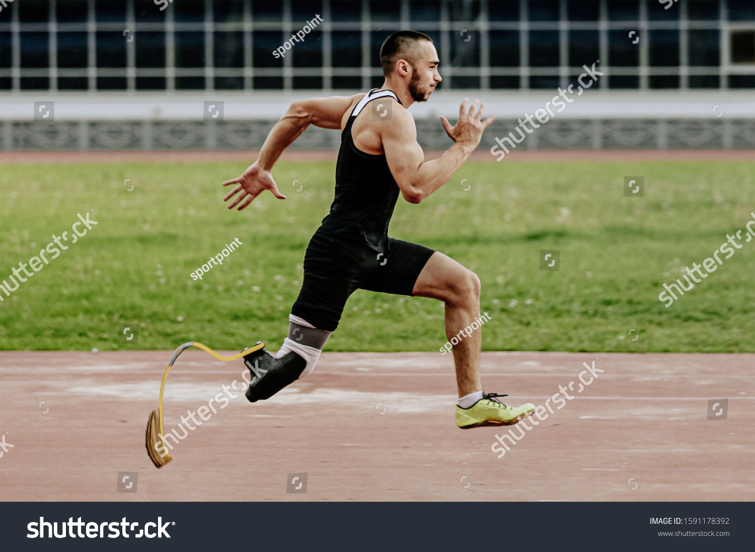 man athlete with prosthetic legs running in track stadium  #1591178392