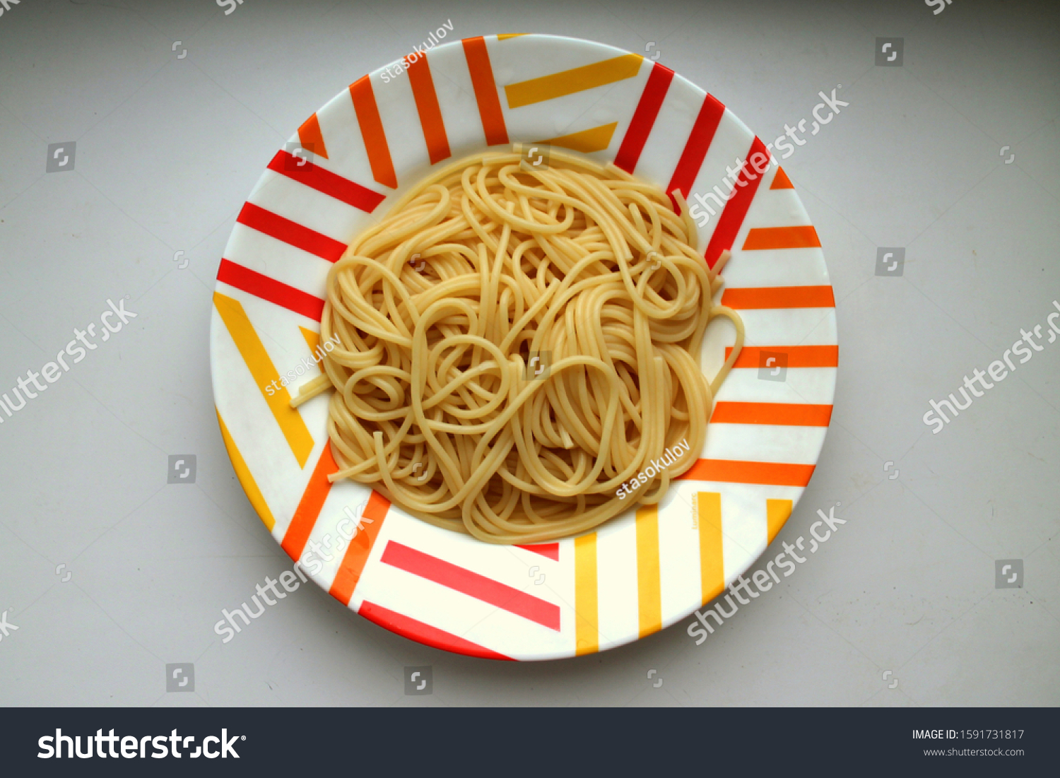 Cooked cooked spaghetti lie in a colorful motley plate #1591731817