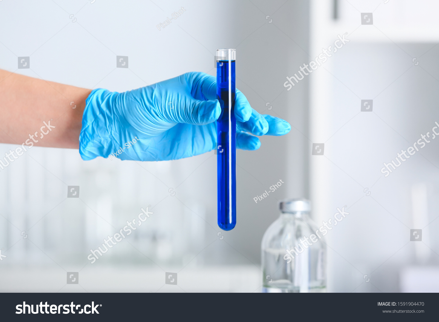 Hand of scientist holding test tube with sample in laboratory #1591904470