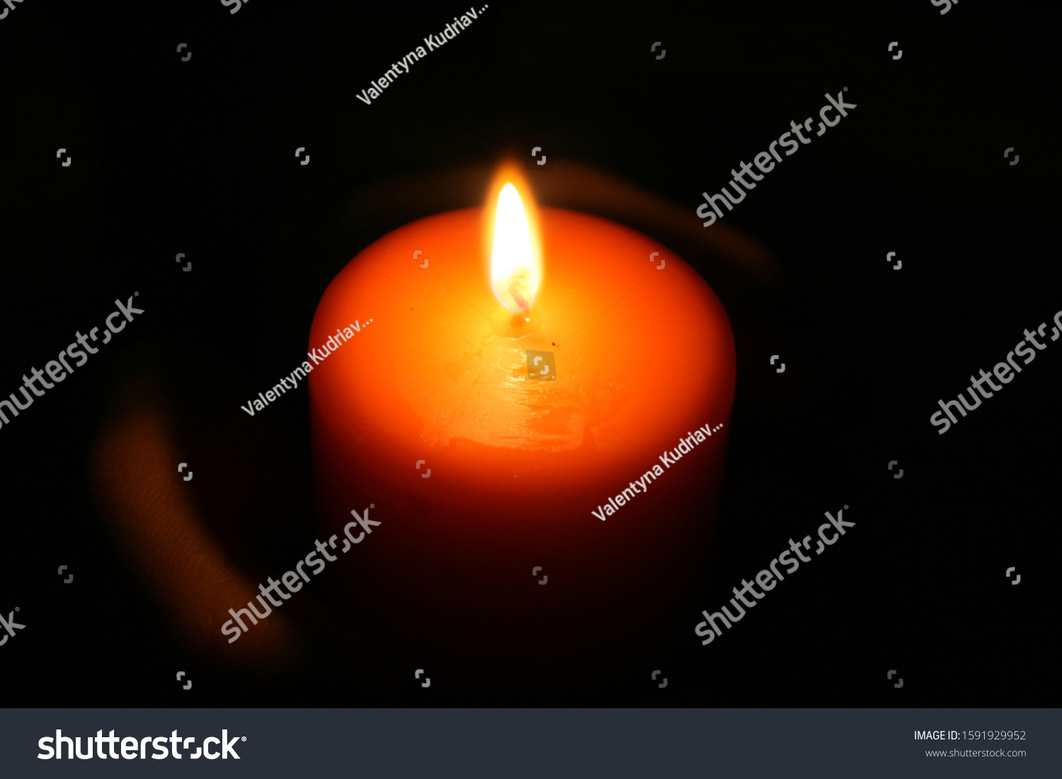 The candle glows in the darkness in the hands #1591929952