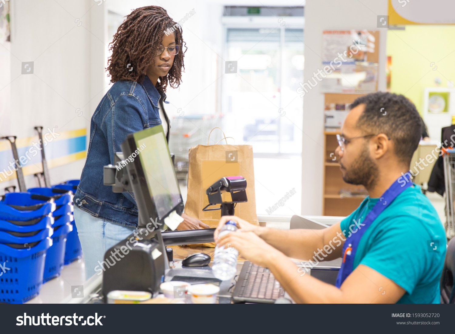 Side view of male cashier scanning goods at checkout. Young woman with buying groceries in supermarket. Shopping concept #1593052720