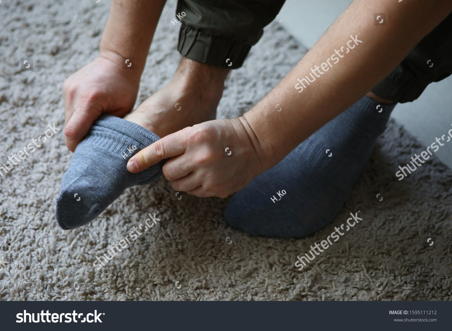 Man at home in morning puts gray socks on his leg. For a long time do not change clothes concept #1595111212