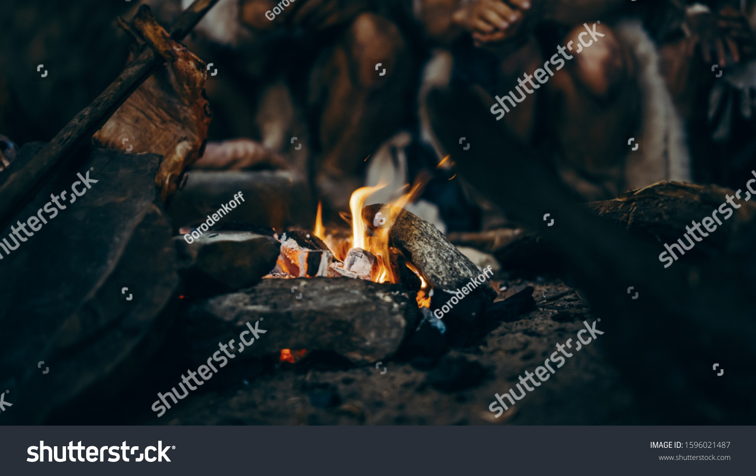 Close-up of Tribe Prehistoric Hunter-Gatherers Trying to Get Warm at the Bonfire, Holding Hands over Fire, Cooking Food. Neanderthal or Homo Sapiens Family Live in Cave at Night. #1596021487