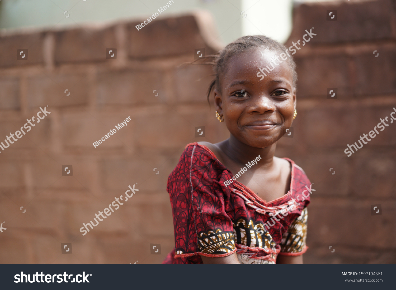 Smiling African Girl With a Wet Face After Having Taken A Sip From The Water Borehole #1597194361