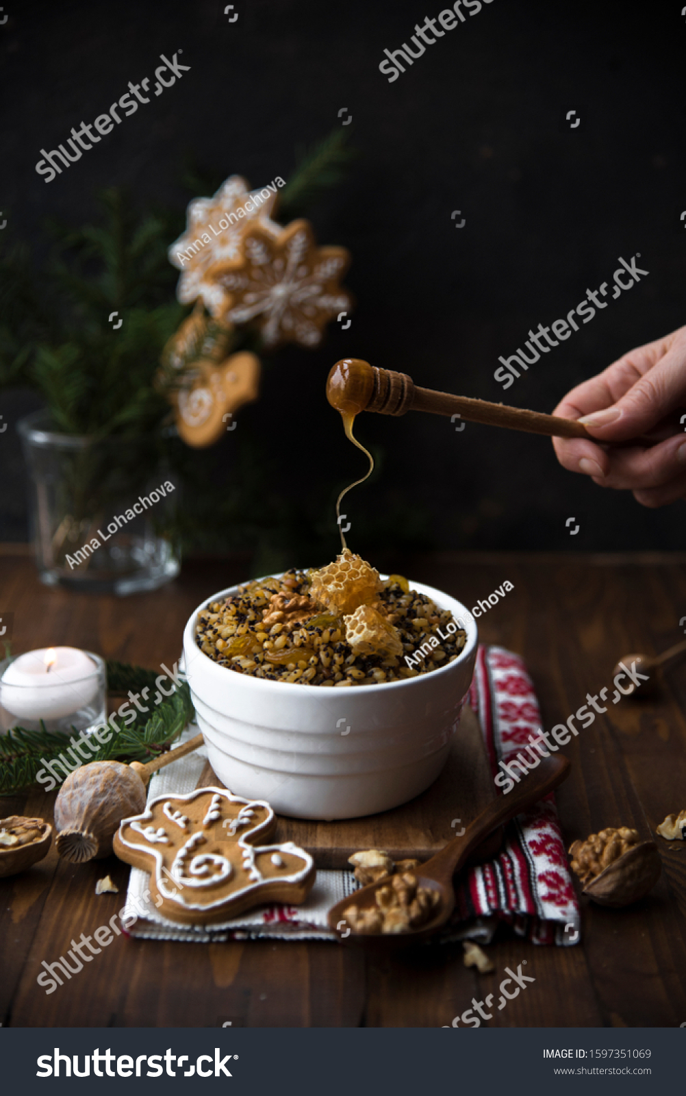 kutya, rushnyk (traditional traditional ukrainian textile), candles and christmas decor on a wooden table. hand pours honey. Christmas Slovenian food #1597351069