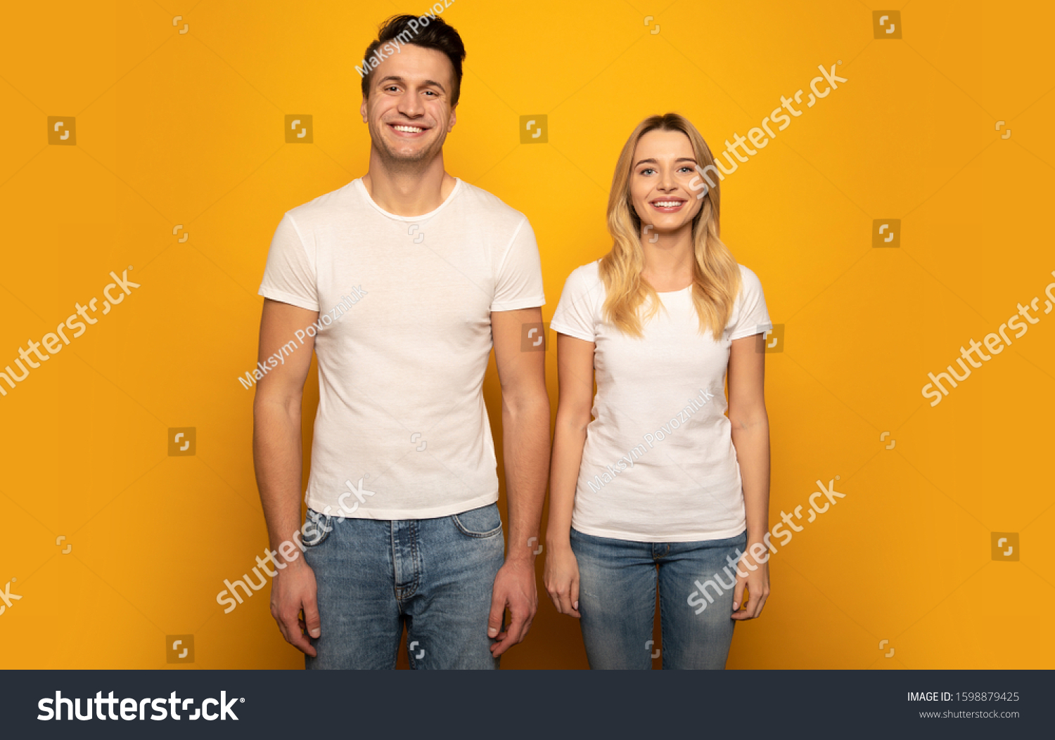 That’s us. Close-up photo of a beautiful couple, who are posing in white t-shirts on a yellow background with their arms down, looking in the camera and smiling. #1598879425