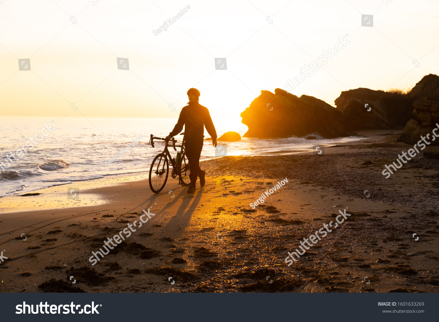 silhouette of young male bicycle rider in helmet on the beach during beautiful sunset #1601633269