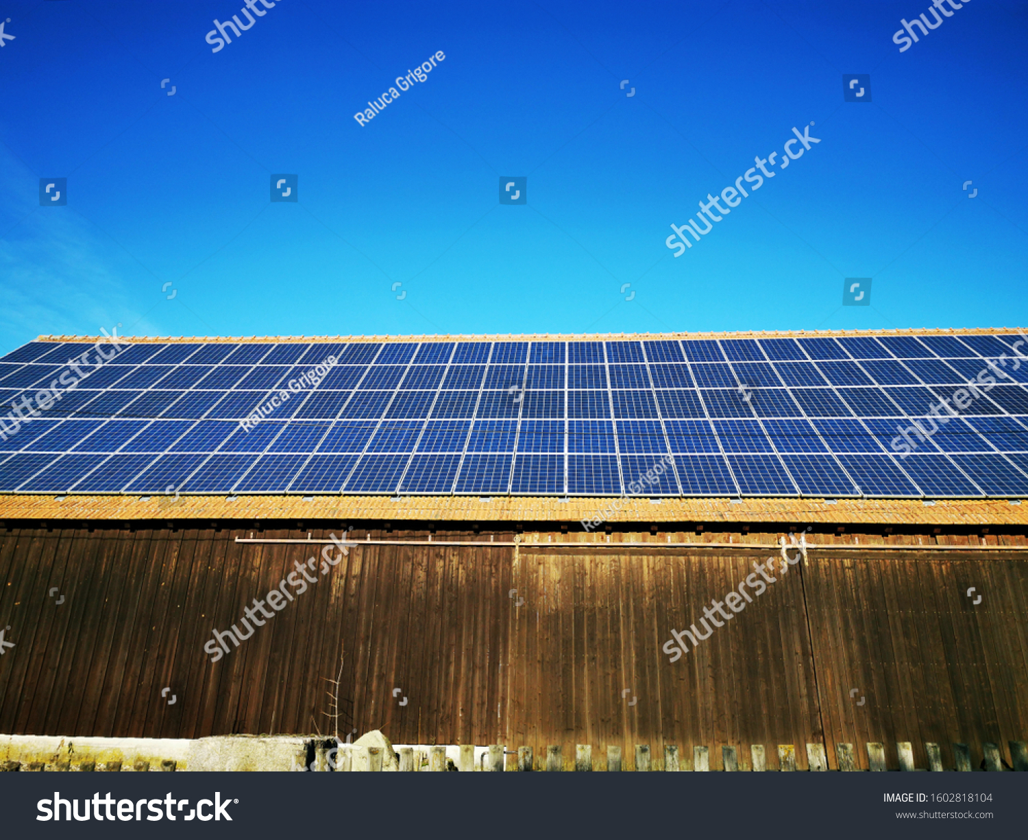 Photovoltaic panels or solar panels on a old wooden barn,with a beautiful blue sky on background,in a small village in the Bavarian south region of Germany ,Europe. #1602818104
