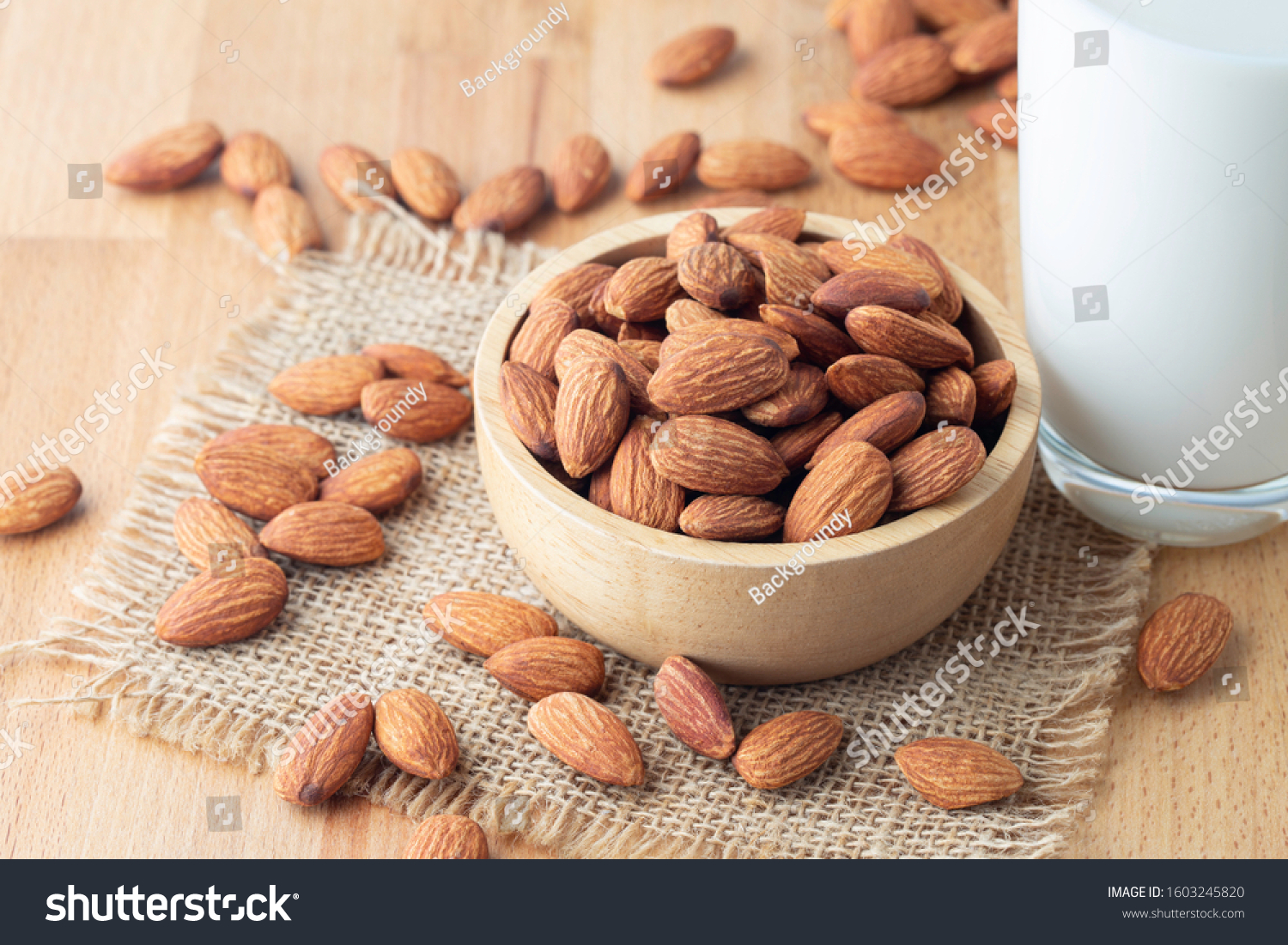 Almond seeds in a bowl wood on the sackcloth And a glass of milk on table wooden background #1603245820
