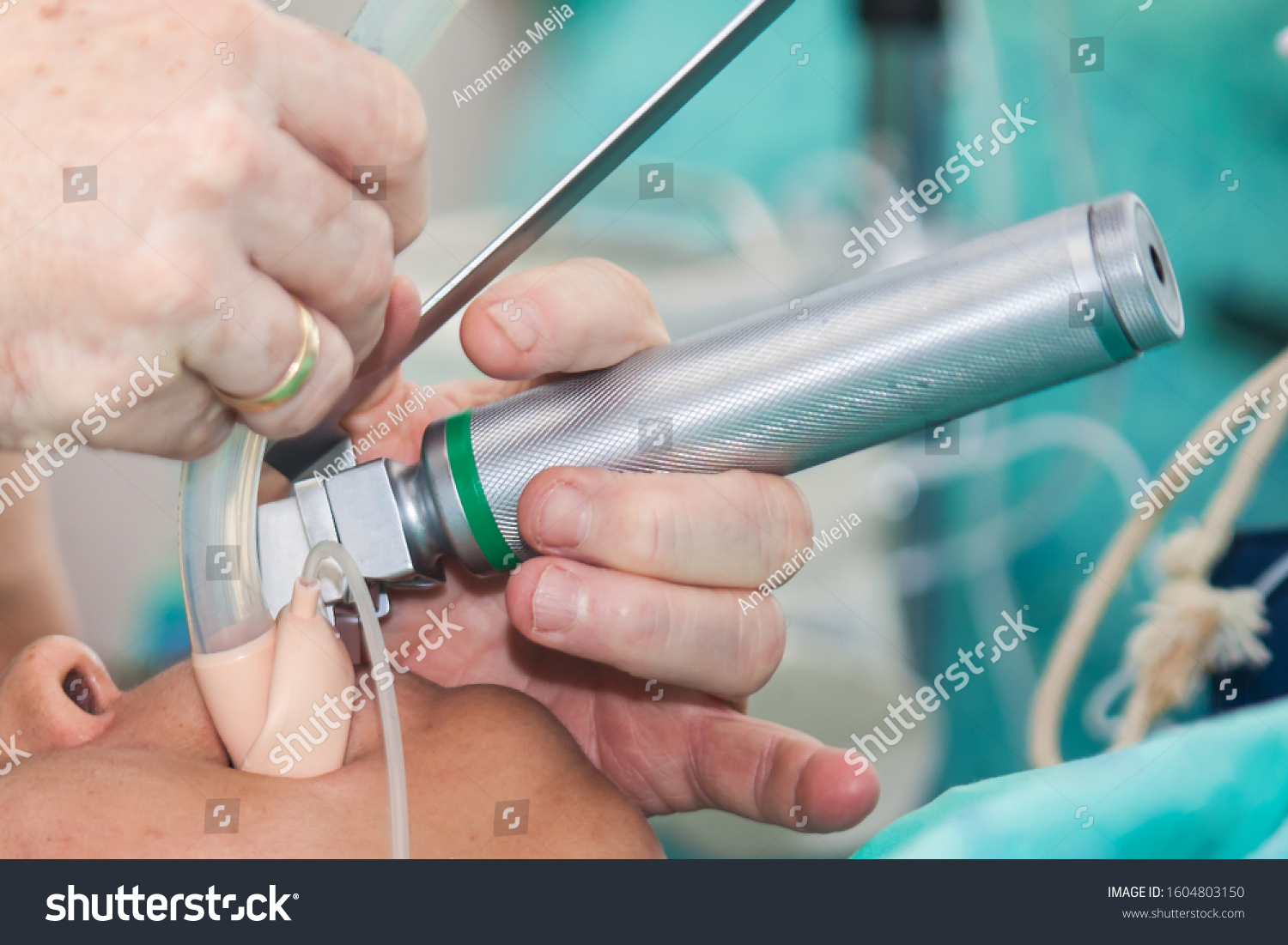 Anesthesiologist performing an endotracheal intubation to a female patient at the beginning of a surgery #1604803150