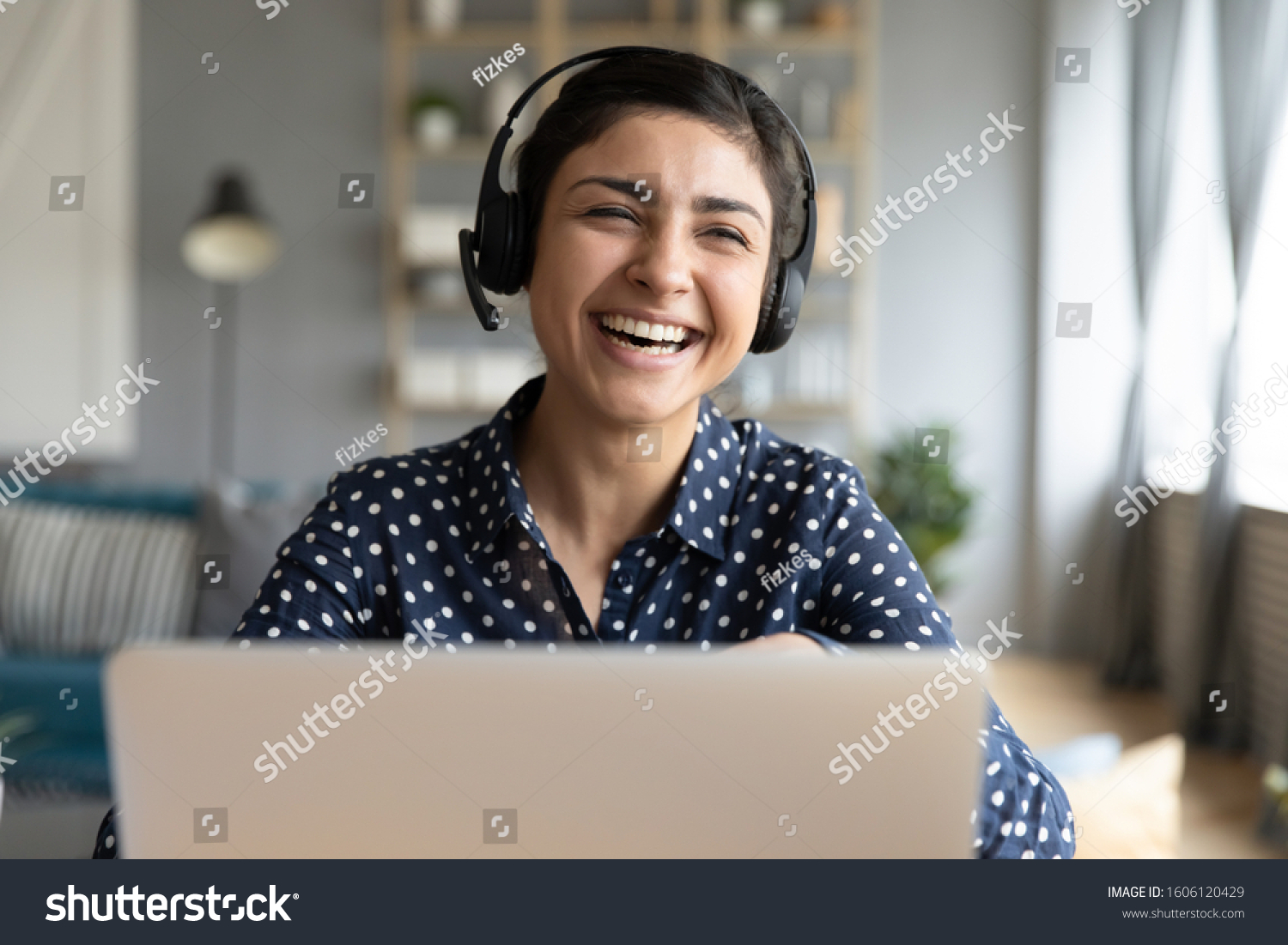 Cheerful indian woman wear headset laugh using laptop video stream conference call teach online, happy ethnic girl student gamer tutor have fun watch webinar web cam education entertainment concept #1606120429