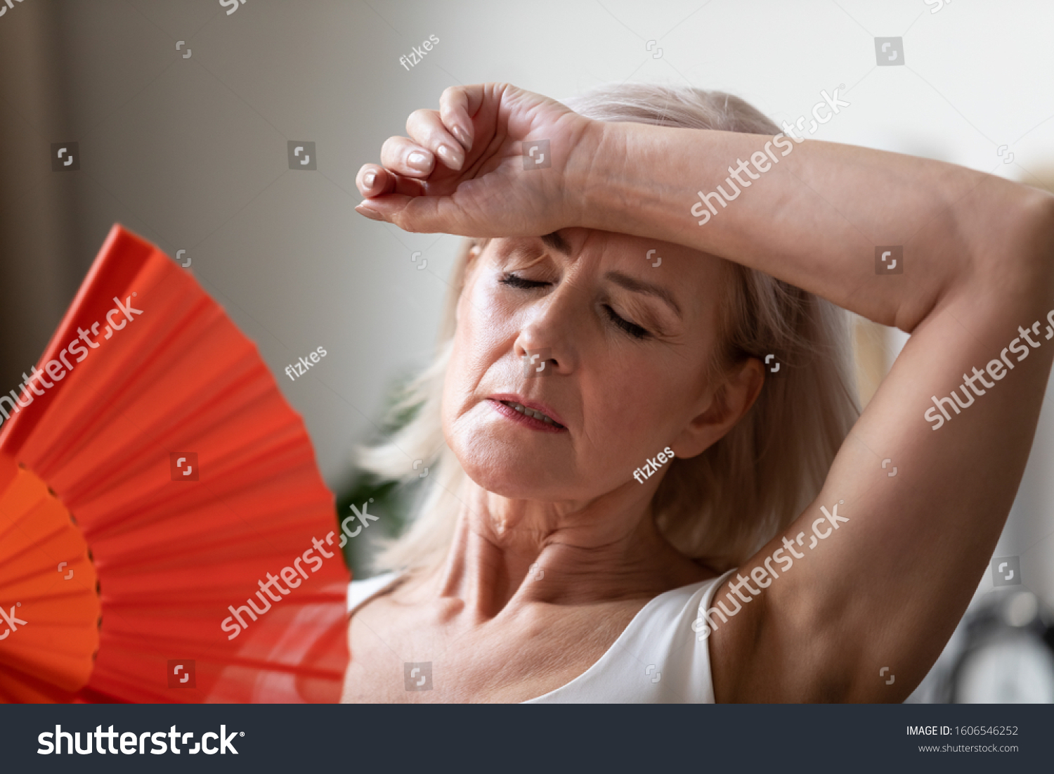 Close up of senior woman feel unwell suffer from hot weather heatstroke have no air conditioner at home, elderly unhealthy female pensioner struggle with heat use hand fan or waver cooling down #1606546252