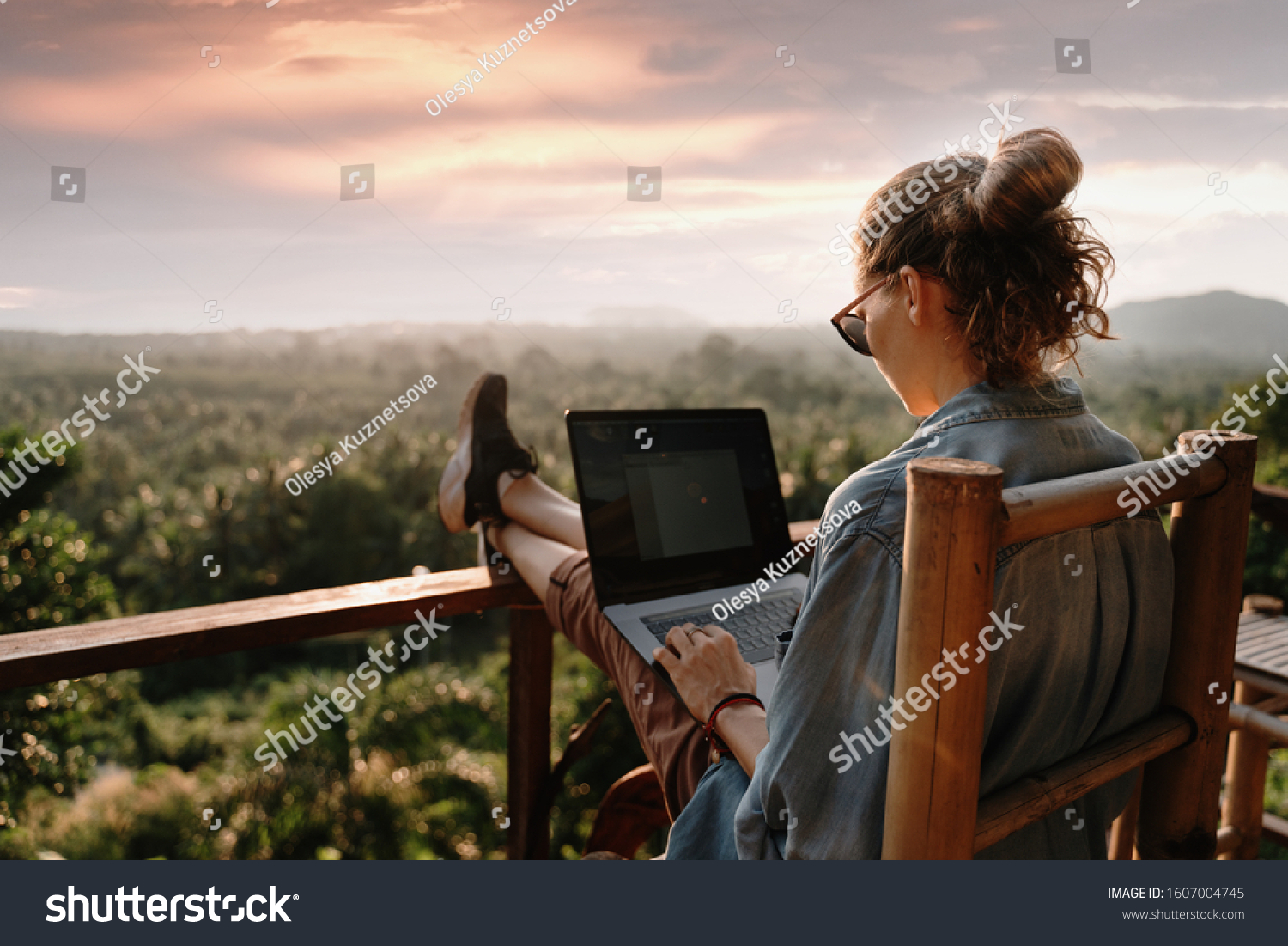 Young business woman working at the computer in cafe on the rock. Young girl downshifter working at a laptop at sunset or sunrise on the top of the mountain to the sea, working day.