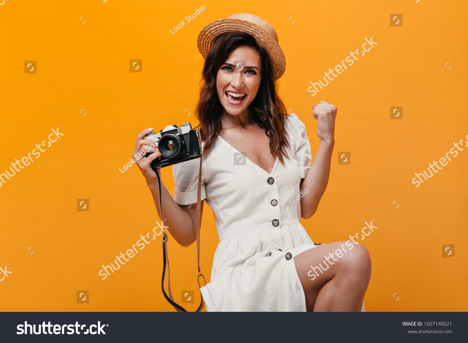 Girl rejoices, holds camera and looks into camera on orange background #1607140021