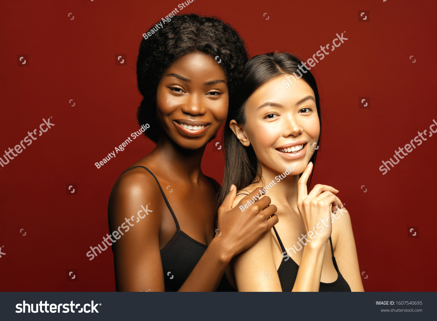 Multi Ethnic Group of beauty Womans with diffrent types of skin  together and looking on camera. Two Diverse ethnicity women -  African and Asian posing and smiling against red background. #1607540695