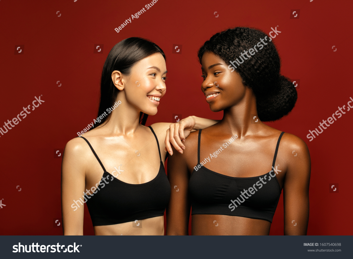 Multi Ethnic Group of beauty Womans with diffrent types of skin  together and looking on camera. Two Diverse ethnicity women -  African and Asian posing and smiling against red background. #1607540698