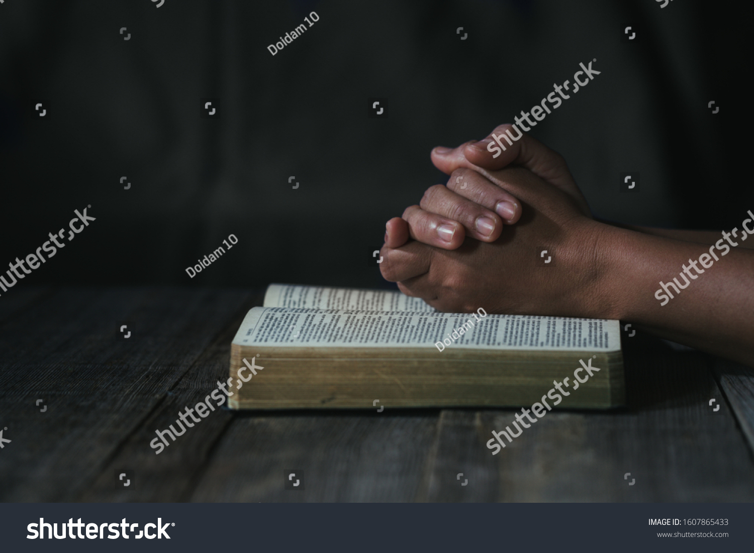 Hands folded in prayer on a Holy Bible in church concept for faith, spirituality and religion, woman praying on holy bible in the morning. woman hand with Bible praying. #1607865433