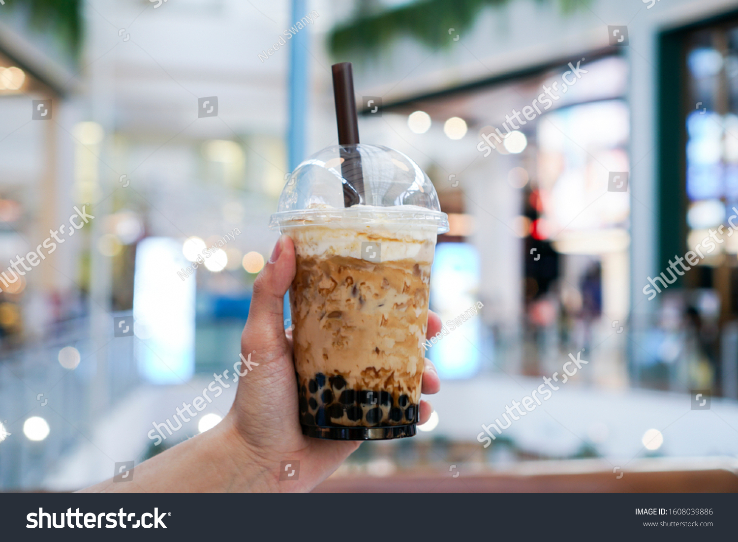 Iced Boba/Bubble Milk tea. A plastic cup of milk tea with boba/bubble tapioca pearls and brown sugar syrup, topped with milk foam. #1608039886
