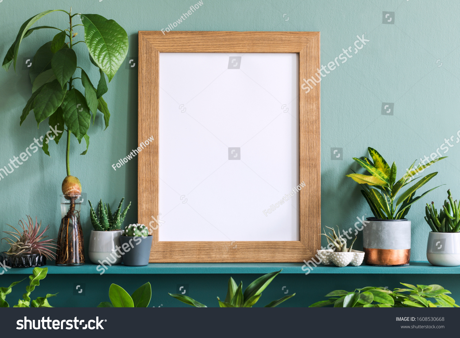 Interior design of living room with brown mock up photo frame on the green shelf with beautiful plants in different hipster and design pots. Elegant personal accessories. Home gardening. Template. 