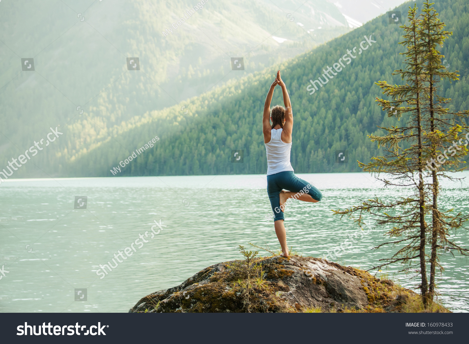 Young woman is practicing yoga at mountain lake #160978433