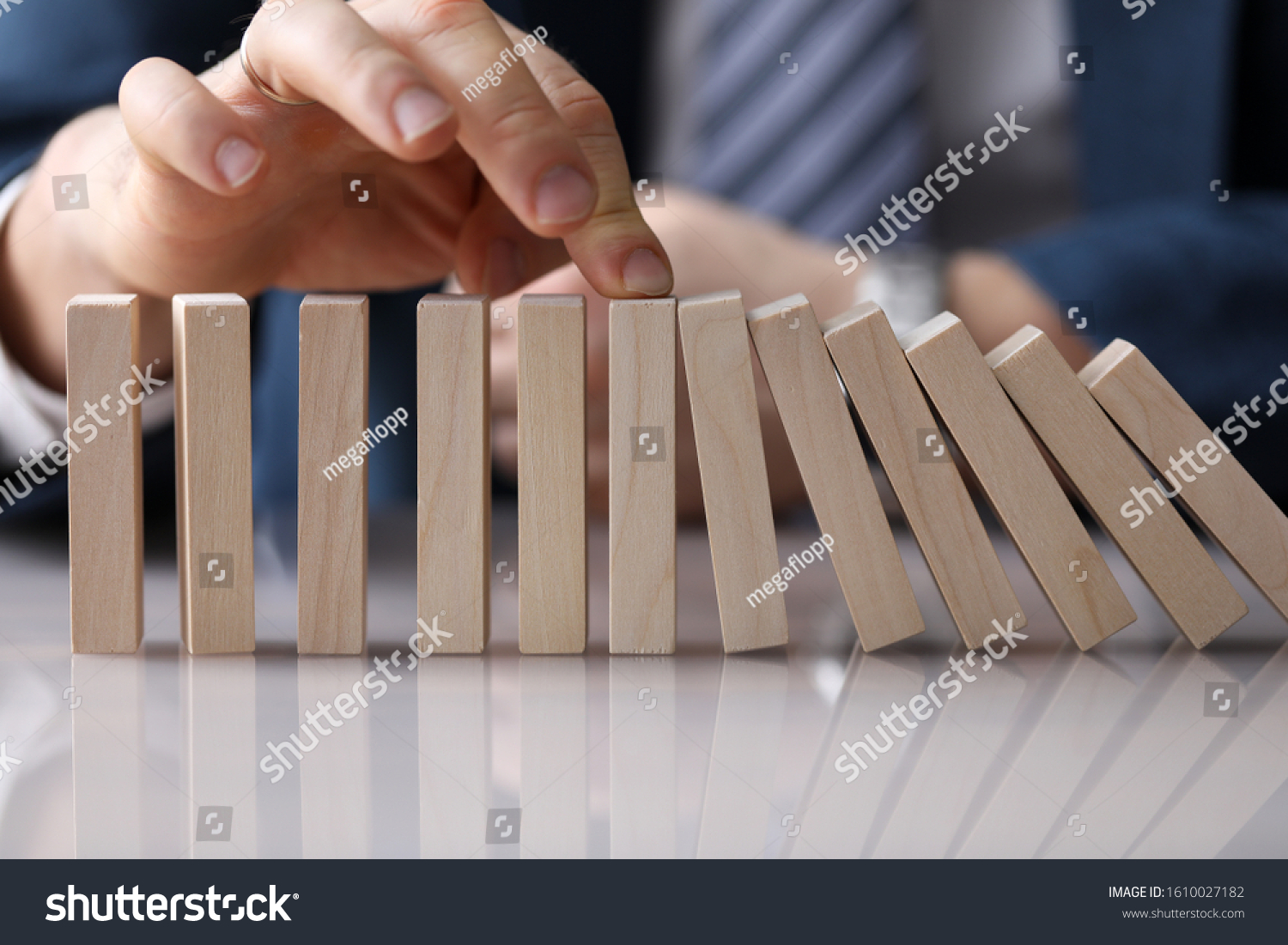 Close-up view of businessmans hand pushing wooden blocks placed in line on table. Falling identical same colour bricks. Business and strategy planning concept #1610027182