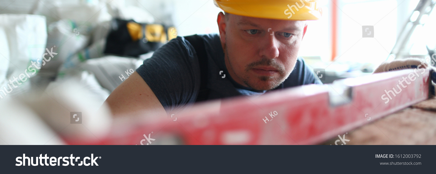 Portrait of smart male using special equipment to remain certain quality of construction method level. Bearded builder wearing hard gloves to keep hands unharmed. Building concept #1612003792