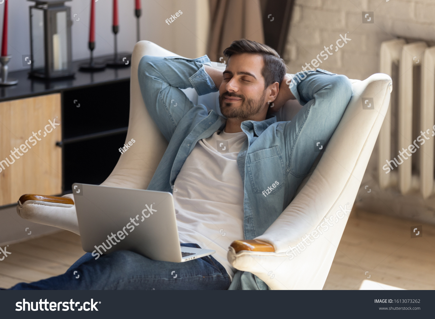 Peaceful young man daydreaming in comfortable armchair with computer on knees. Calm guy taking break after working with laptop, controlling fatigue or stress, resting alone in living room at home. #1613073262