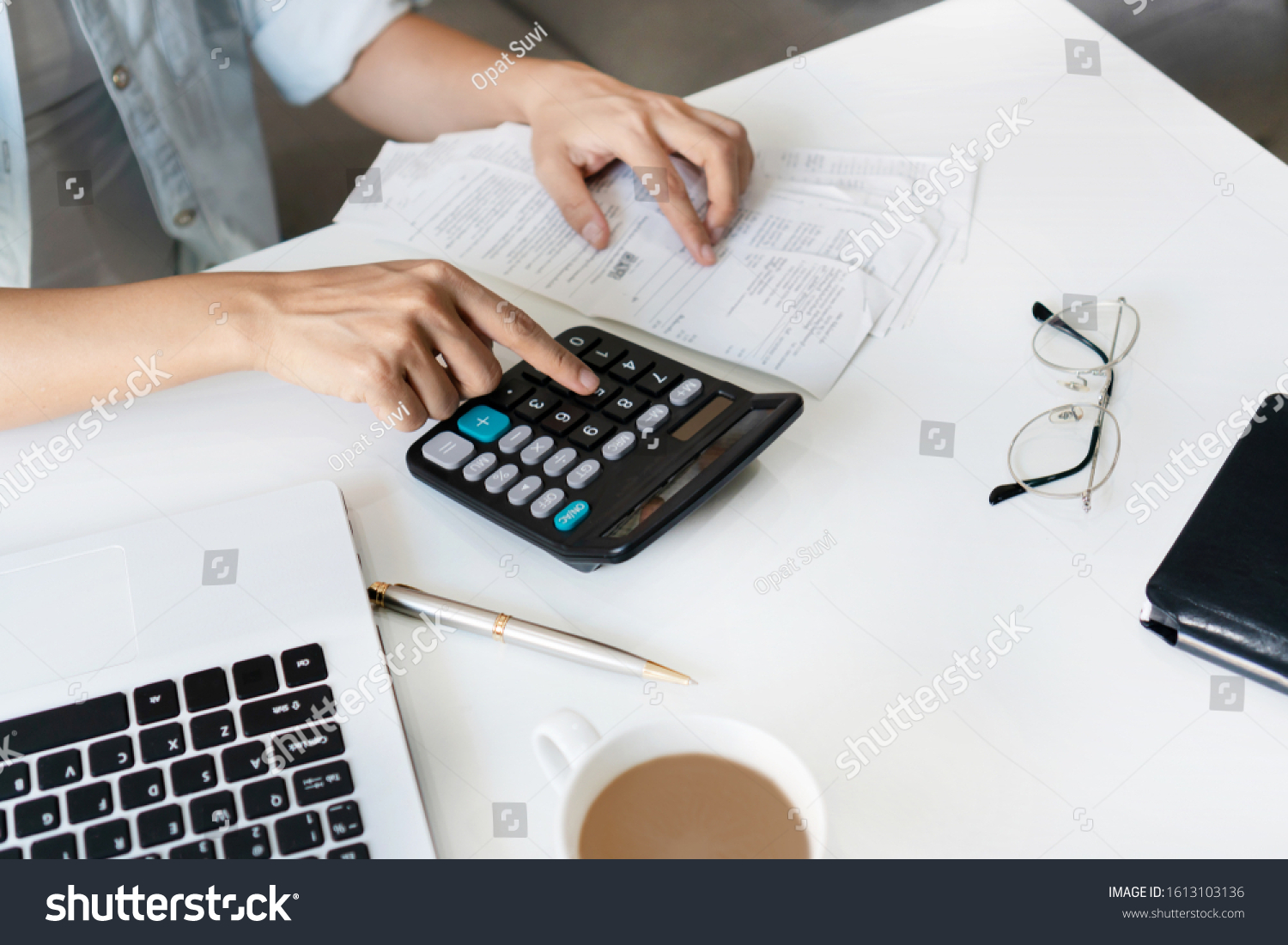 Pretty young Asian woman using calculator to calculate home expenses and tax in living room at home.  #1613103136