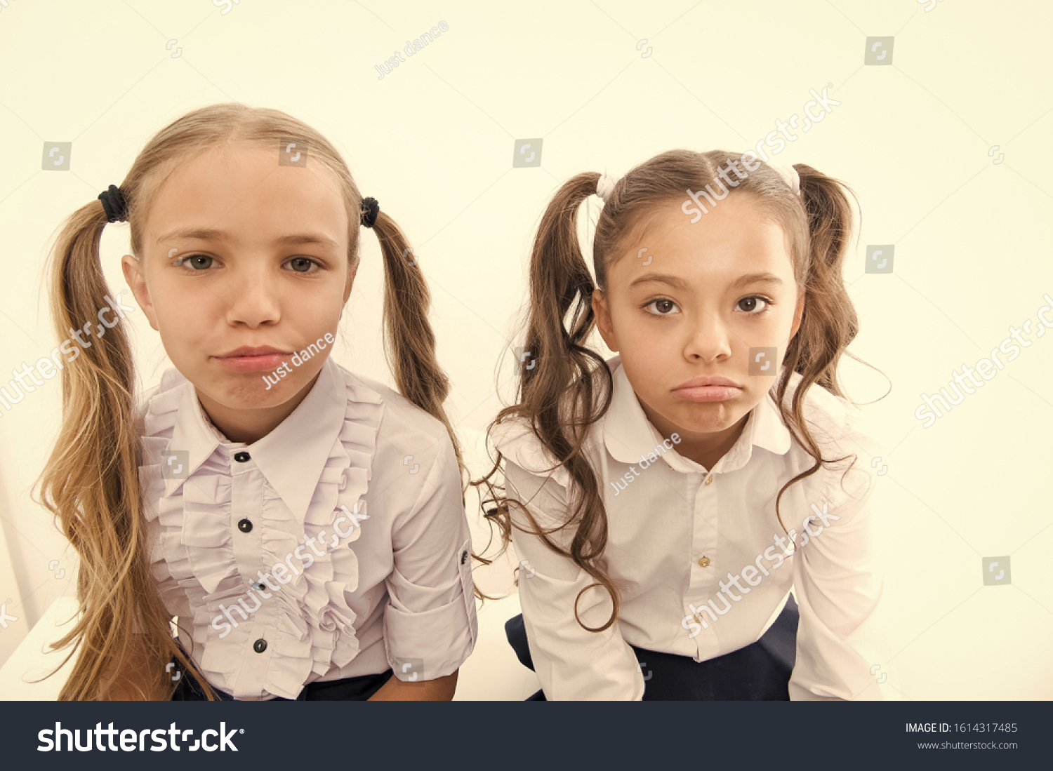 Unhappy cuties. Unhappy little schoolchildren isolated on white. Adorable small girls with unhappy emotions looking in camera. Unhappy because of school starts. #1614317485