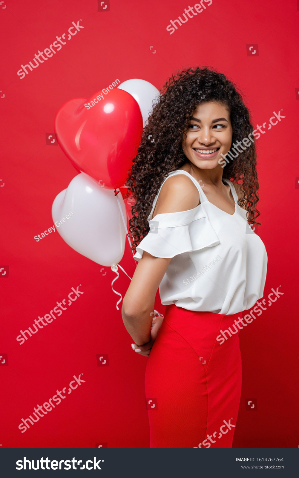 playful cheerful black woman holding colorful balloons isolated on red #1614767764