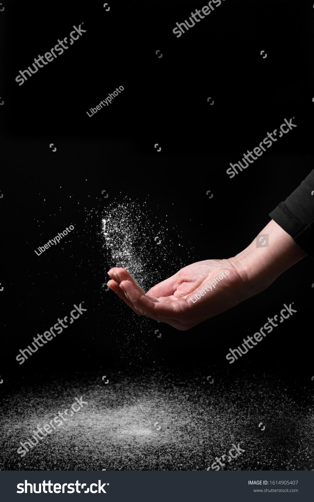 Creative image of hand scattering sugar powder on a dark background #1614905407