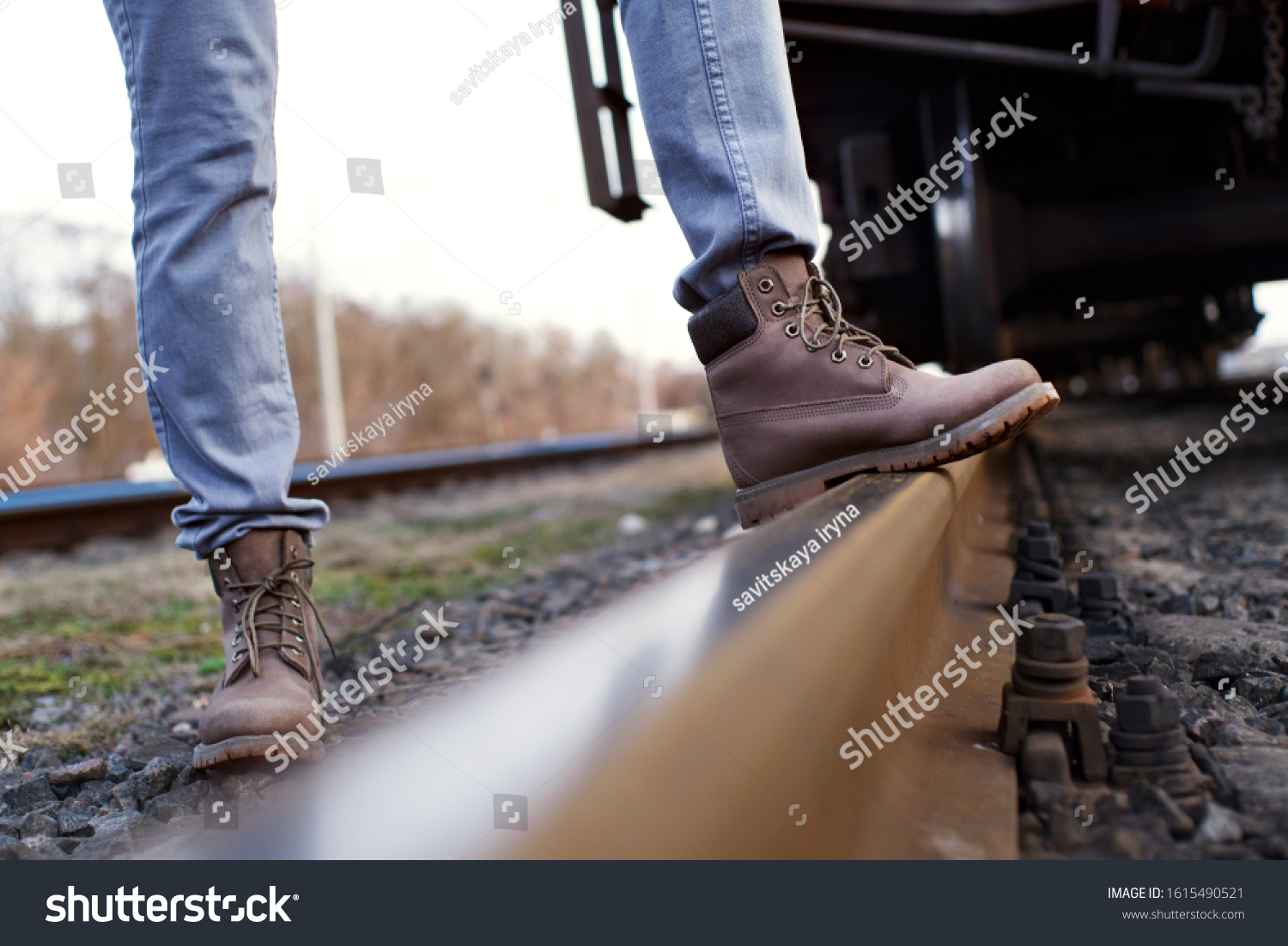 Girl in boots walks through the railroad tracks in autumn #1615490521