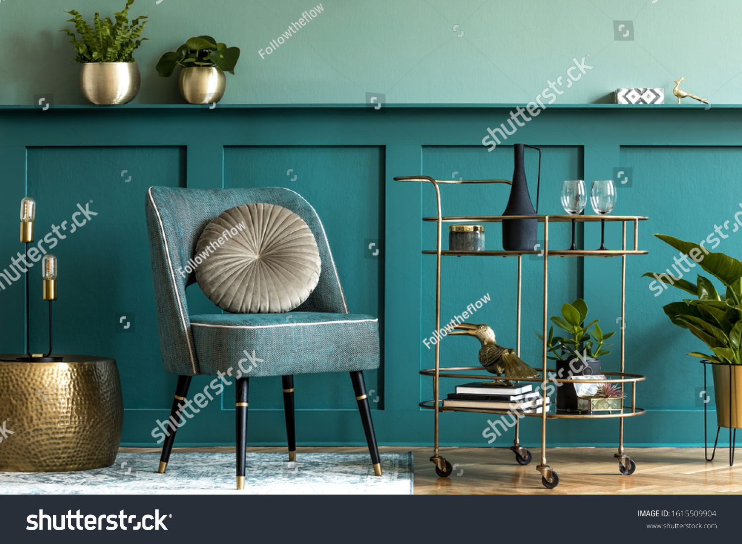 Interior design of luxury living room with stylish armchair, gold liquor cabinet, a lot of plants and elegant personal accessories. Green wall panelling with shelf. Modern home decor. Template.  #1615509904