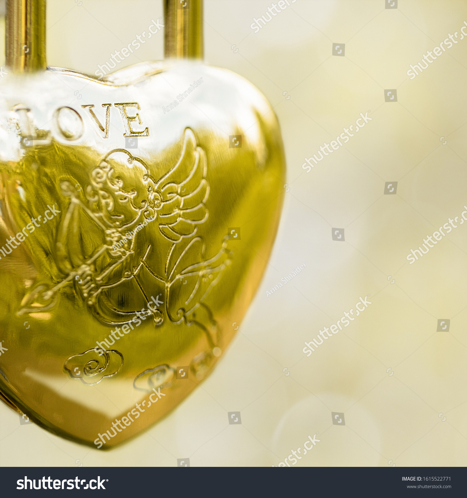  Hinged gold lock in the form of a heart, the inscription love angel with an arrow on a blurred background. Symbol of wedding. #1615522771