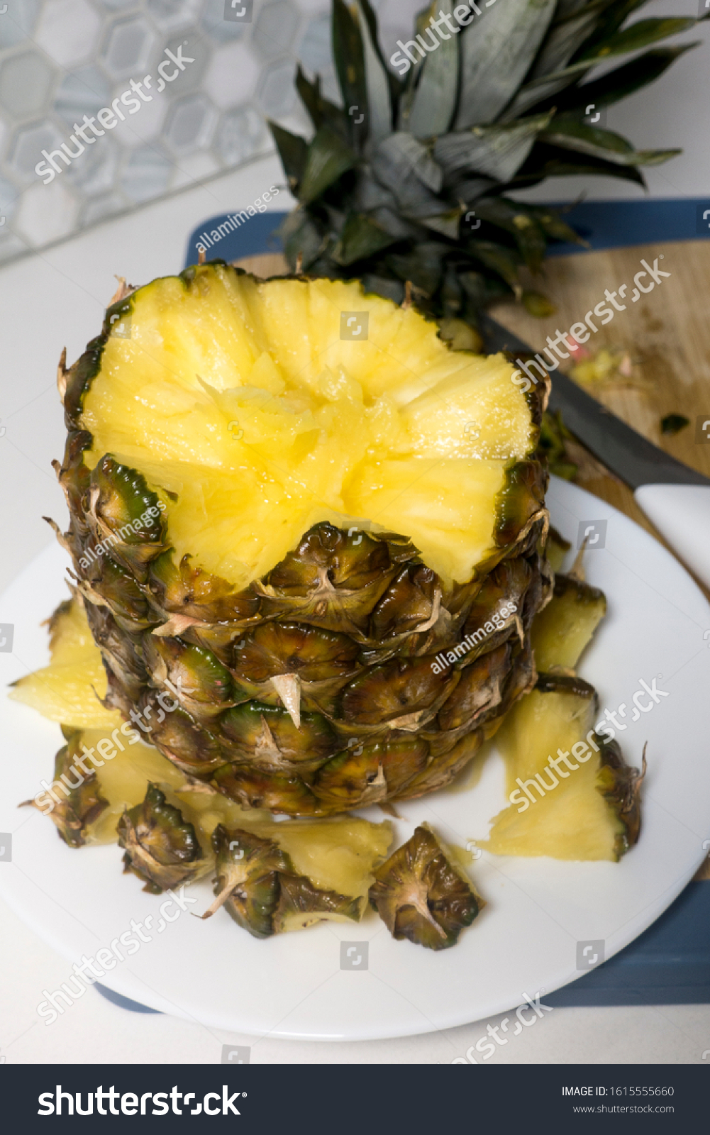 A wonderful composition of sliced pineapple on white plate made of a creative concept, preparing different alternative compositions of tropical fruit on white table on wooden board. #1615555660