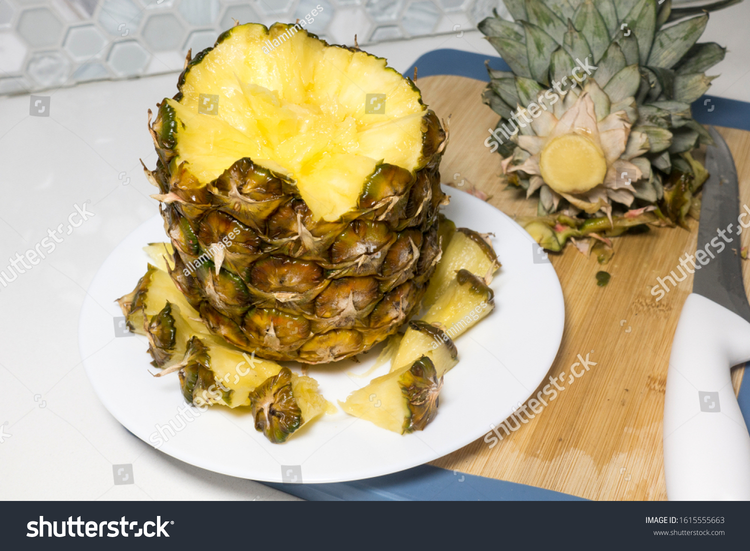 A wonderful composition of sliced pineapple on white plate made of a creative concept, preparing different alternative compositions of tropical fruit on white table on wooden board. #1615555663