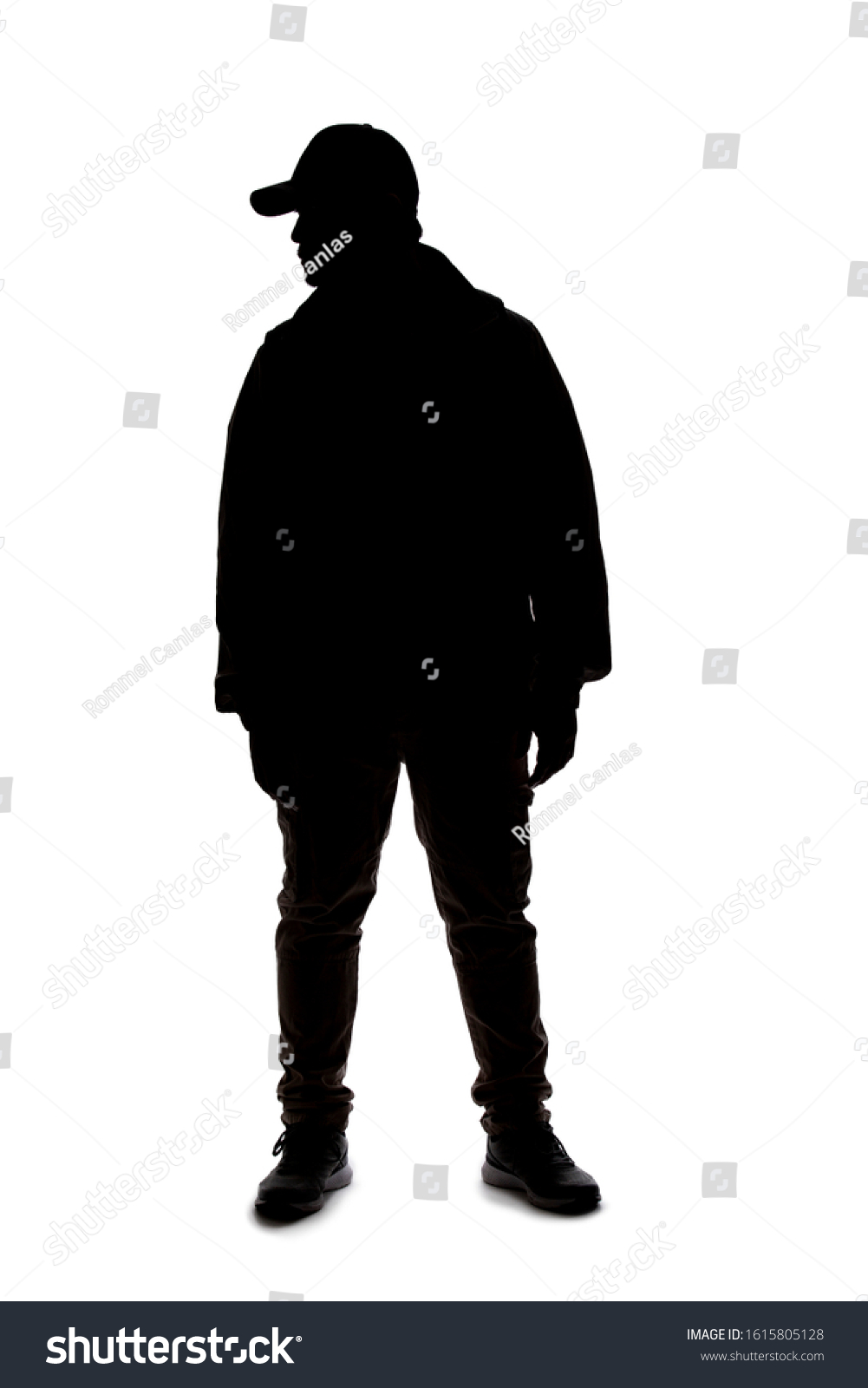 Silhouette of a man wearing a backpack looking like a traveler or hiker trekking.  He is patiently standing and waiting  #1615805128