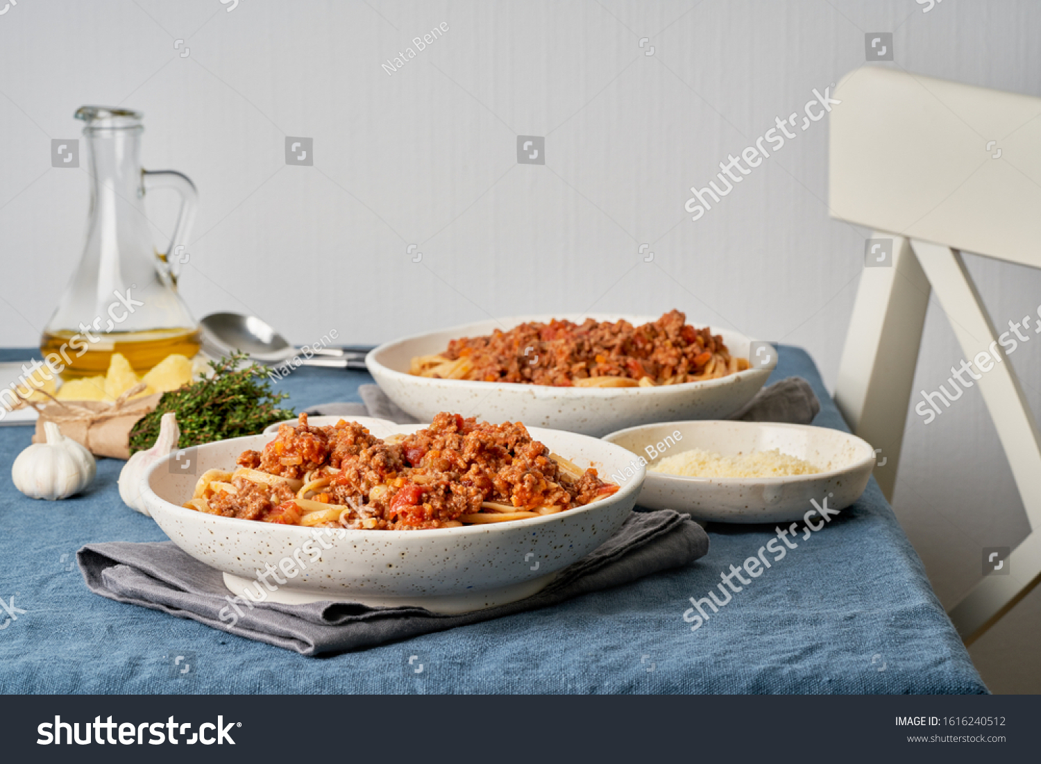 Pasta Bolognese Linguine with mincemeat and tomatoes. Italian dinner for two at the table, dark blue tablecloth, chair, homeliness. Side view #1616240512