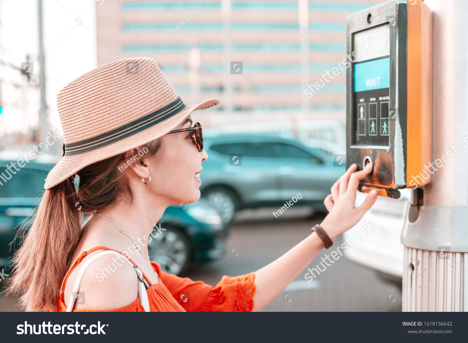 A girl presses a button to cross an adjustable pedestrian crossing on a busy street. Urban development concept #1618156642
