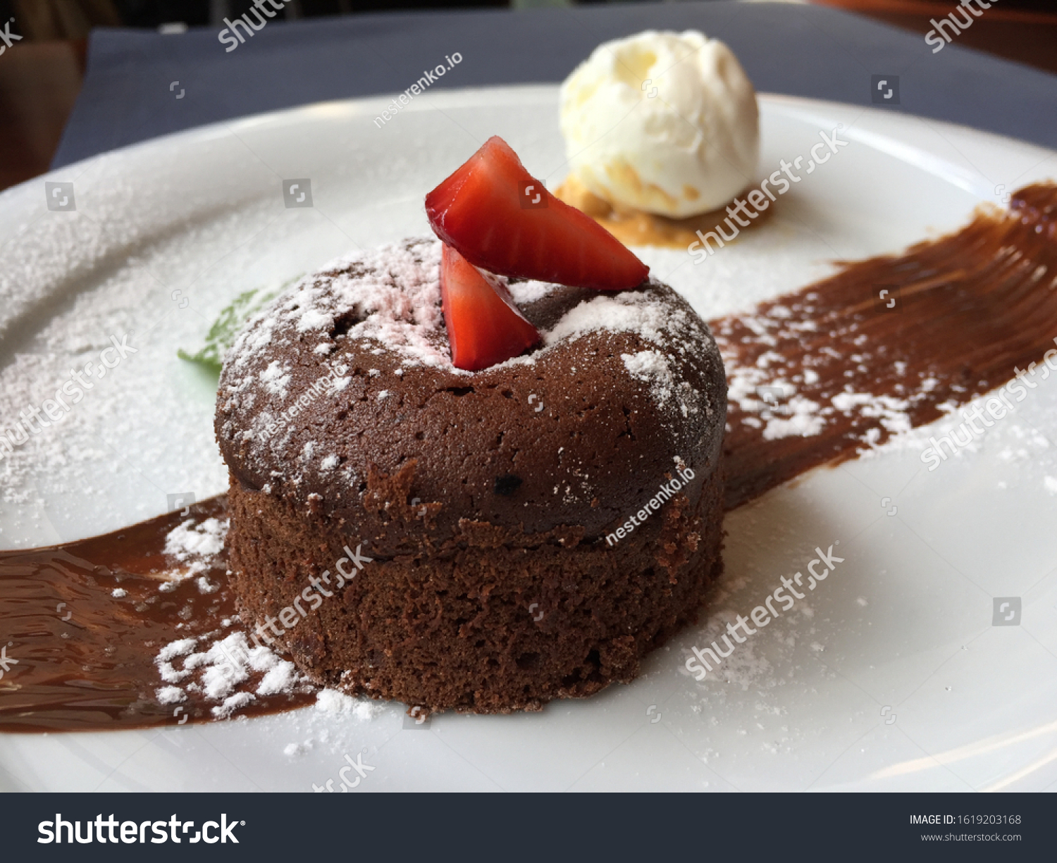 petit gâteau, chocolate fondant, dessert composed of a small chocolate cake with crunchy rind and mellow filling that is served hot with vanilla ice cream on a plate. #1619203168