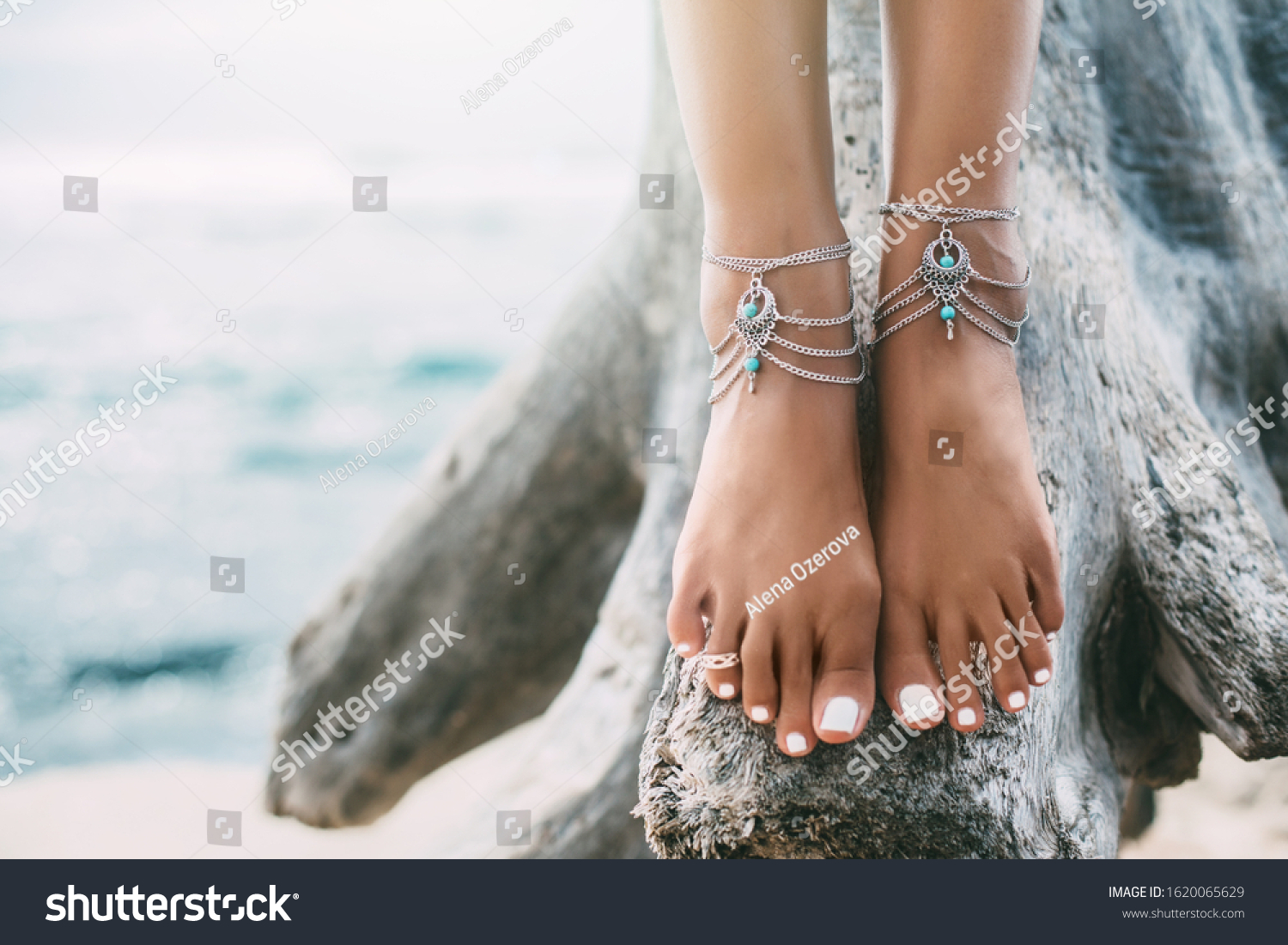Boho styled girl wearing indian silver jewelry on the beach, tanned legs close up #1620065629