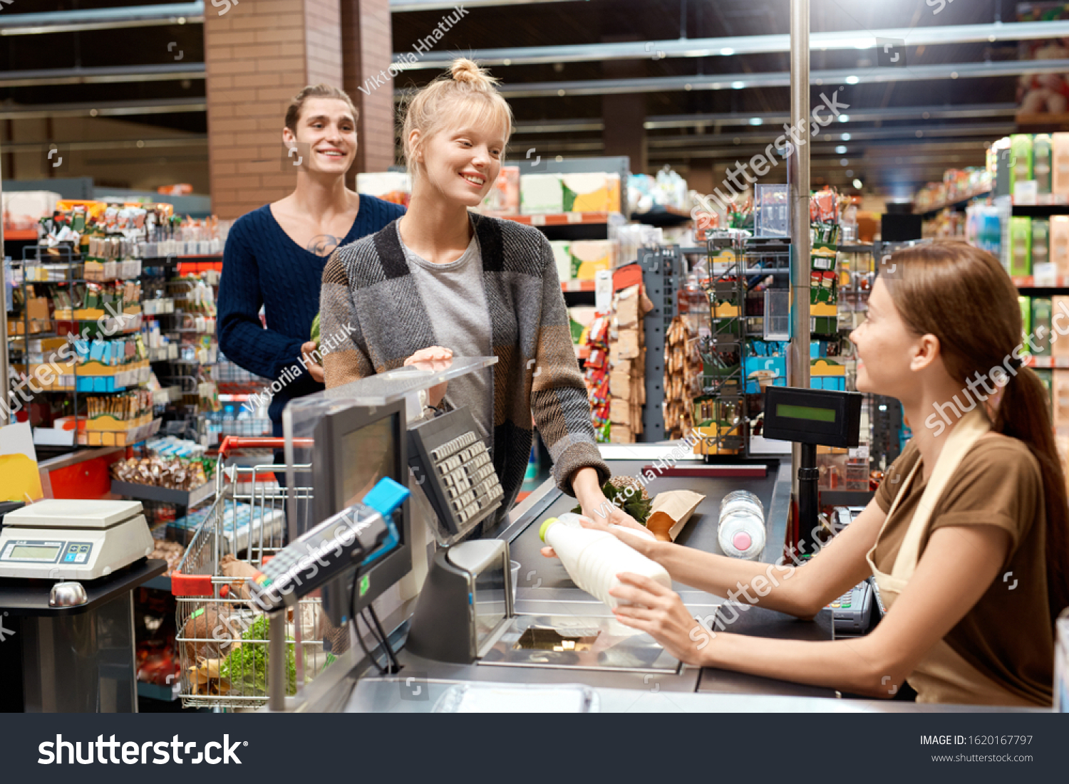 Young couple at the supermarket doing daily shoppings checkout at cashier counter smiling happy #1620167797