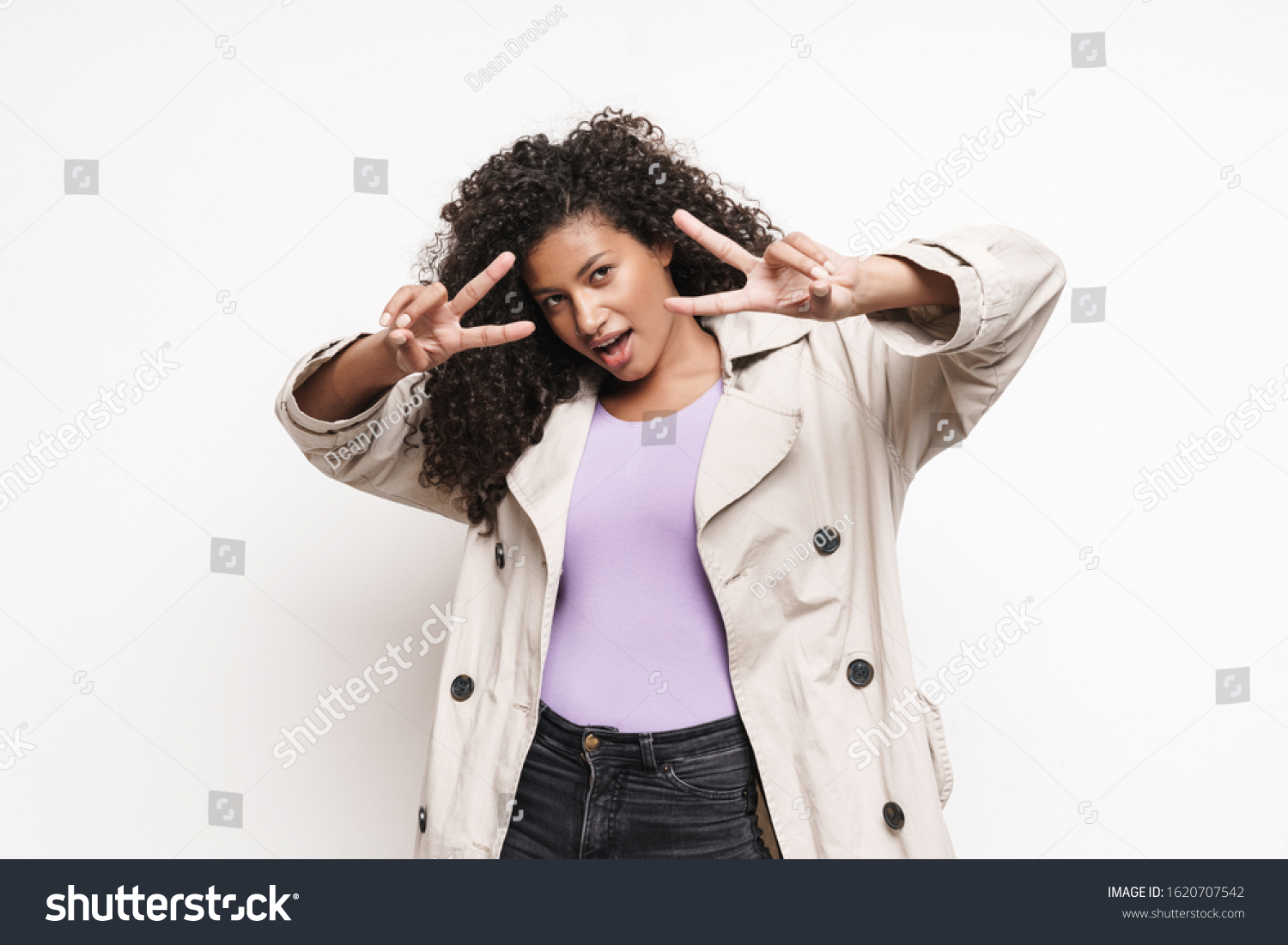 Cheerful playful attractive young african woman wearing autumn jacket having fun isolated over white background, showing peace gesture #1620707542