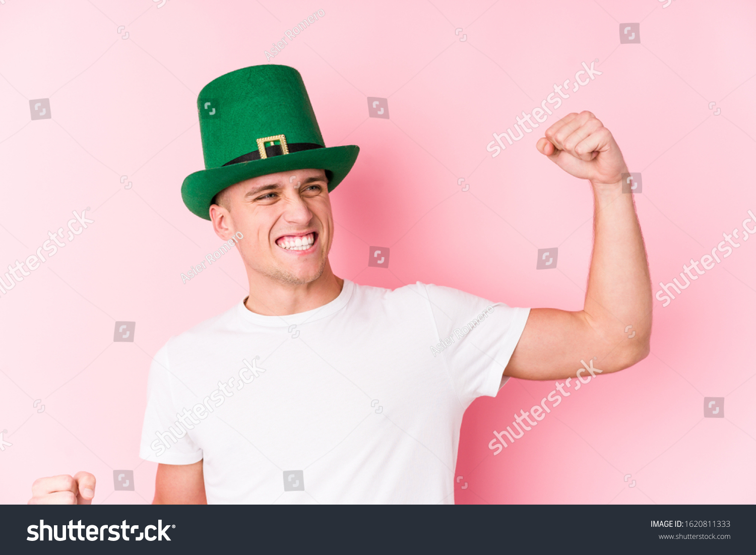 Young caucasian man celebrating saint patricks day raising fist after a victory, winner concept. #1620811333