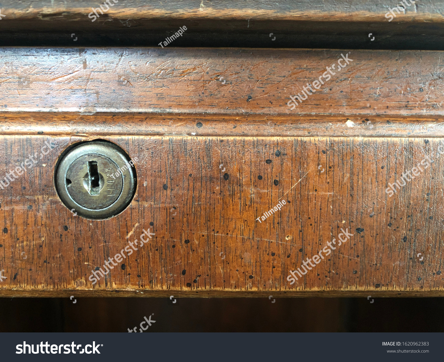 An old desk lock on a wooden drawer #1620962383