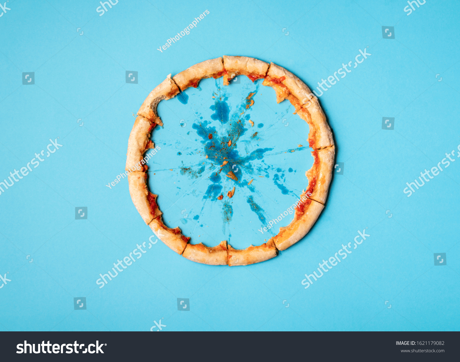 Pizza crust in a circle on blue background and grease traces. Flat lay of just pizza crust and crumbs. Eaten pizza context. Diet pizza funny concept. #1621179082
