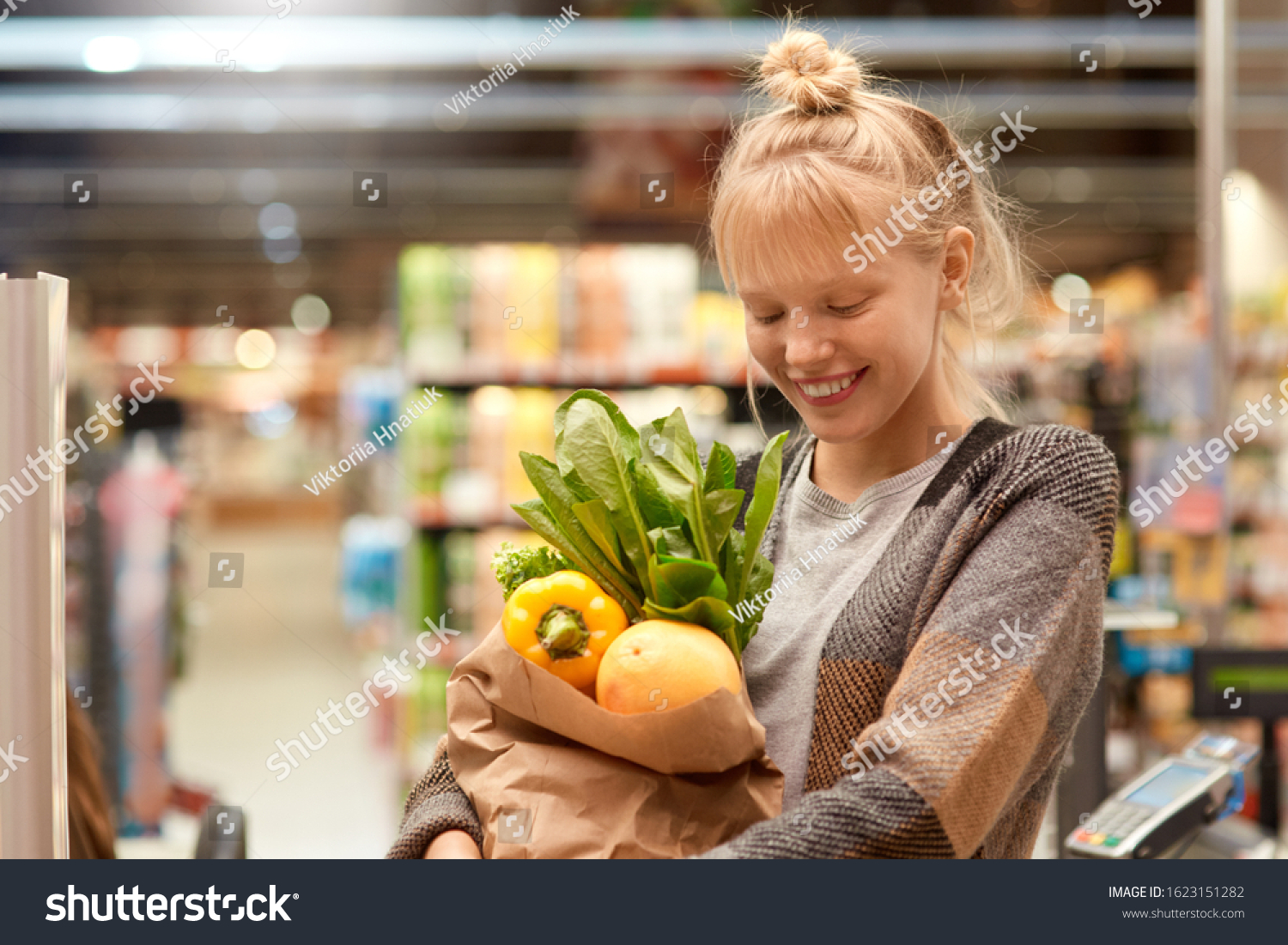 Young woman at the supermarket standing holding paper bag with shoppings fresh organic vegetables looking down laughing happy close-up just walk out shopping technology #1623151282