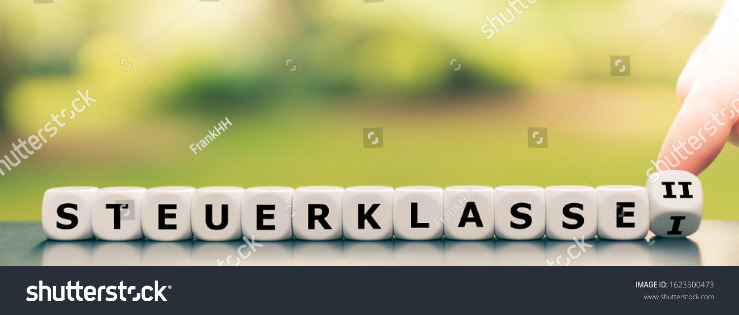 Hand turns a dice and changes the German expression "Steuerklasse I" ("German tax class 1") to ("Steuerklasse II" ("German tax class 2"), #1623500473