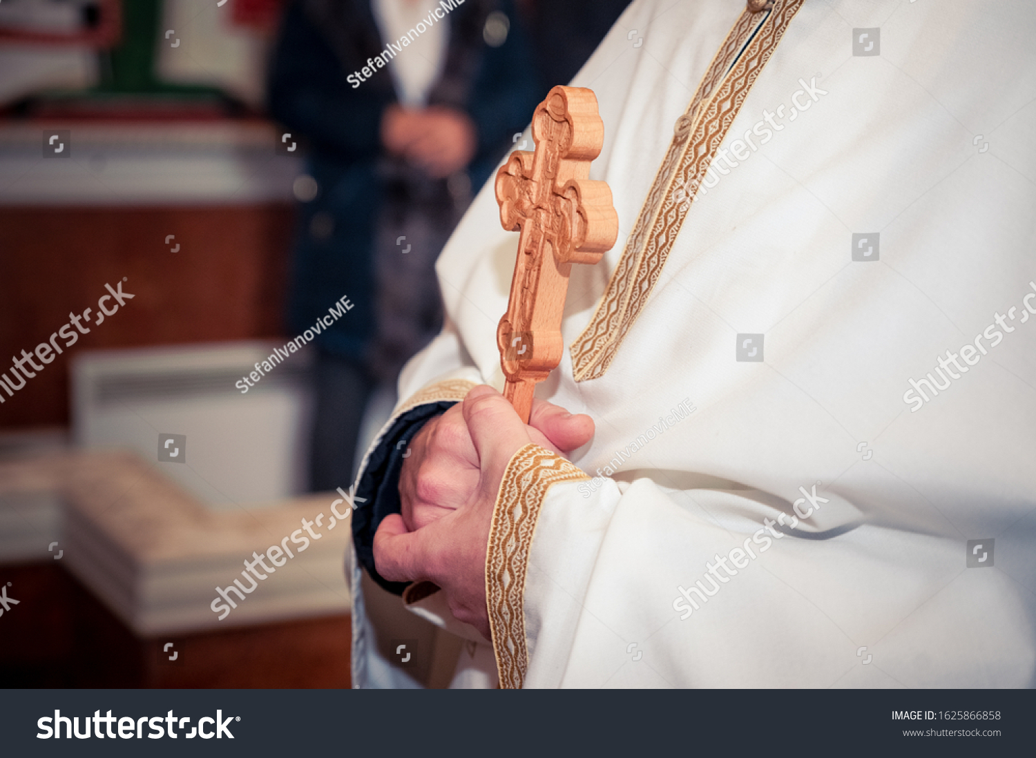 Ortodox priest holding a cross while christening  #1625866858